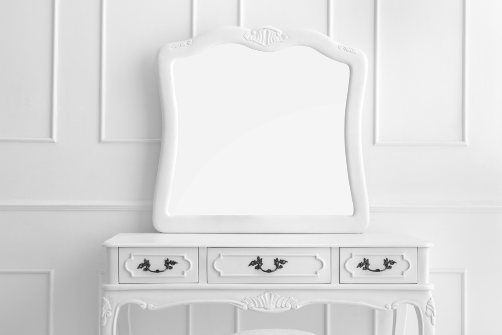 a white vanity against a white wall with a large mirror
